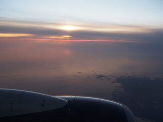 Fototapeta na wymiar Sun Setting from an Airplane Window