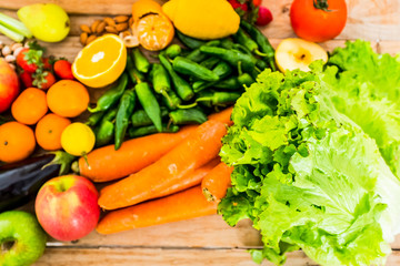 Close up of mixed and coloured seasonal vegetables and fruit on a wooden table - concept of healthy food and vitamin - vegan or vegetarian nutrition lifestyle