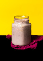 Smoothie de frambuesa con frambuesa regadas en trapo guinda en fondo amarillo sobre color negro