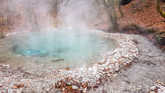 A natural thermic spring in Maibachl, Austria during autumn. The thermic pool is located in the middle of the forest. Healing power of natural water. The steam rises above the water. Relaxation