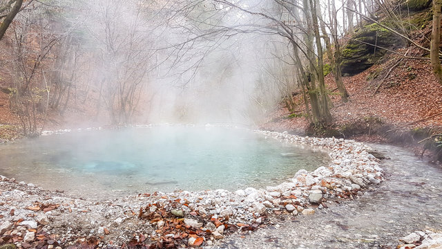 A natural thermic spring in Maibachl, Austria during autumn. The thermic pool is located in the middle of the forest. Healing power of natural water. The steam rises above the water. Relaxation