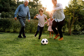 Full length of multi-generation family playing soccer in backyard