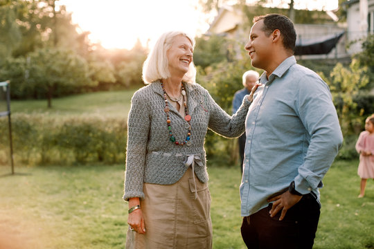 Smiling mother talking with son while standing in backyard