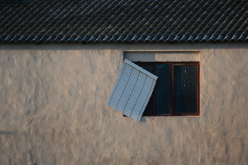 window with broken shutter of an abandoned building