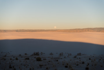 Full moon during sunset at White Sands National Park in Alamogordo, New Mexico. 