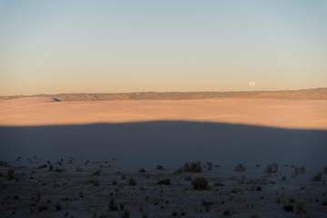 Full moon during sunset at White Sands National Park in Alamogordo, New Mexico. 