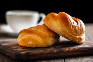 Fresh and rosy buns with cherry on a wooden table and a cup with fragrant tea.