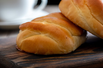 Fresh and rosy buns with cherry on a wooden table and a cup with fragrant tea.