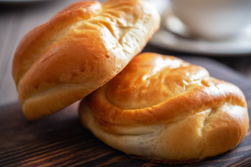 Fresh and rosy buns with cherry on a wooden table and a cup with fragrant tea.