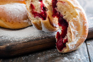 Fresh and rosy buns with cherry on a wooden table