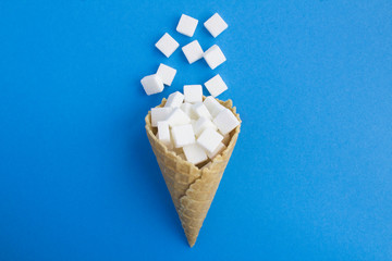 Ice cream cone with white sugar in the center of the blue  background. Top view. Copy space. Location vertical.Creative food collage.