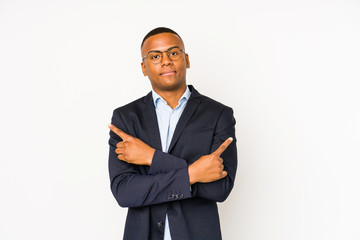 Young business latin man isolated on white background points sideways, is trying to choose between two options.