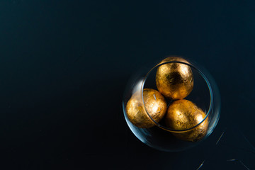 gilded easter eggs in a transparent vase on a concrete background in classic blue color