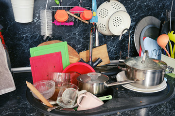 Dirty dishes around the sink in a cluttered kitchen