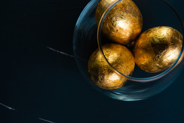 gilded easter eggs in a transparent vase on a concrete background in classic blue color