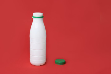 white plastic bottle with a green cap on. red background. copy space