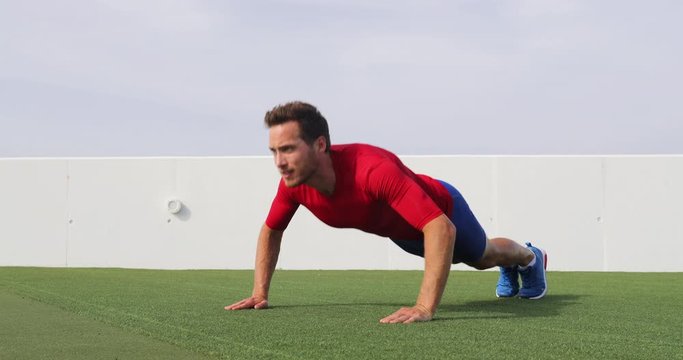 Fitness man doing push ups exercise at outdoor gym. Full body workout athlete doing pushup on grass working out exercising core and arms. SLOW MOTION 59.94 FPS. See other exercises from series.