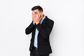 Young caucasian business man against a white background isolated blink through fingers frightened and nervous.