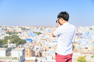 Fototapeta na wymiar Young traveler capture photo of the blue city of Jodhpur in Rajasthan, India