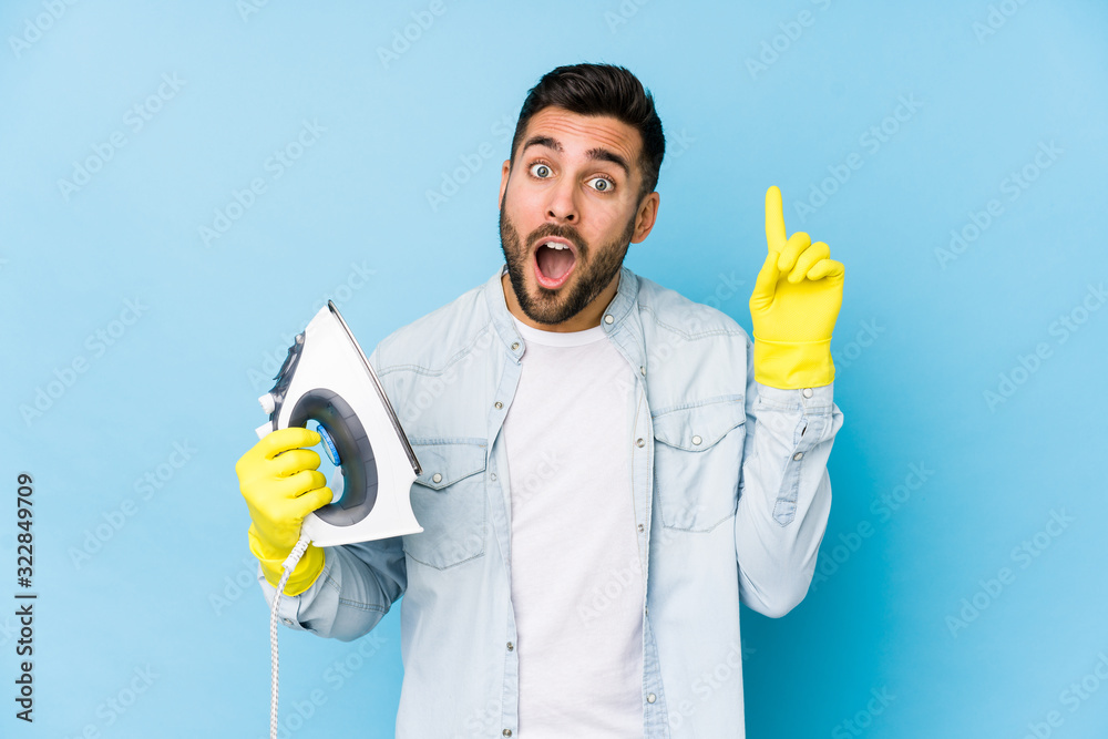 Wall mural Portrait of young man ironing isolated having an idea, inspiration concept.