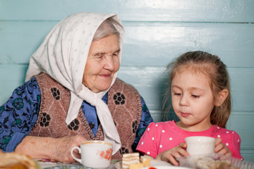 Obraz na płótnie Canvas Grandmother and granddaughter drink tea