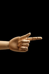 Wooden hand of mannequin for drawing indicates the direction of the index finger on a black background. Point finger. Side view. Art model for drawing. Part of the body - hand, brush. 