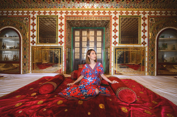 Portrait of young woman in Jaipur City Palace interior room with gold and precious gemstone artwork...