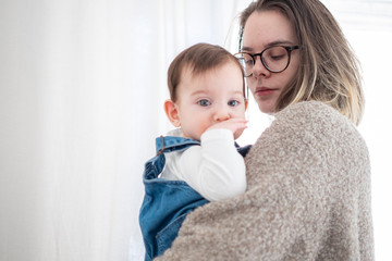 Mother holding little infant baby on white background. Lifestyle family concept. 