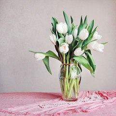 beautiful bouquet of white tulips in a vase on the table on a pink background