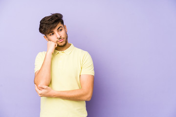 Young arabian man isolated on a purple background who feels sad and pensive, looking at copy space.