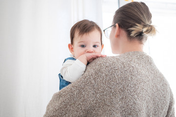 Mother holding little infant baby on white background. Lifestyle family concept. 