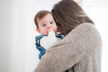 Mother holding little infant baby on white background. Lifestyle family concept. 