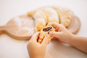 Child's hand stretching to a croissant on a table