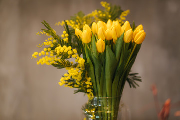 Bouquet of yellow tulips in vase on wooden table