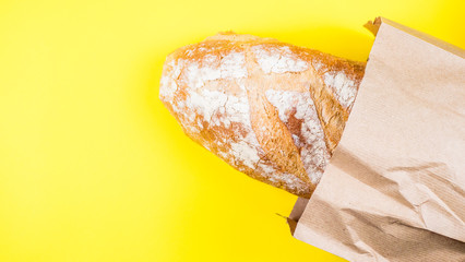 Italian bread in paper ball on yellow background. Top view