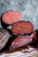 Different types of sausages and smoked meats on dark background.