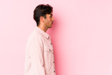 Young caucasian man posing in a pink background isolated gazing left, sideways pose.