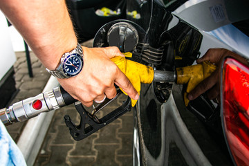 Pumping gas at gas pump. Closeup of man pumping gasoline fuel in car at gas station.