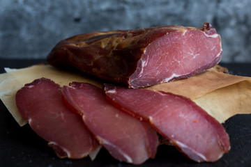 Cold smoked meat on dark background.
