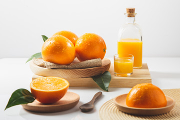 Oranges, oranges slices, orange leaves, and glass containers with orange juice on white background.