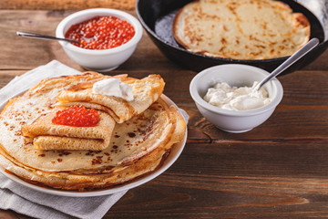 Stack of russian pancakes blini with red caviar, fresh sour cream