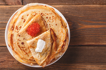 Stack of russian pancakes blini with red caviar, fresh sour cream