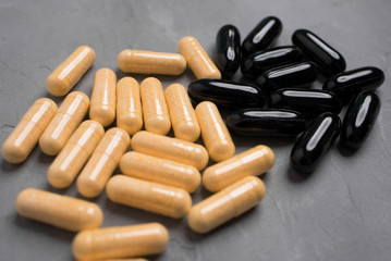 Yellow and black capsule pills on a gray background
