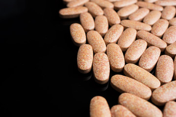 Large pills close-up on a black background on the right side of the frame.