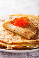 Stack of russian pancakes blini with red caviar, fresh sour cream