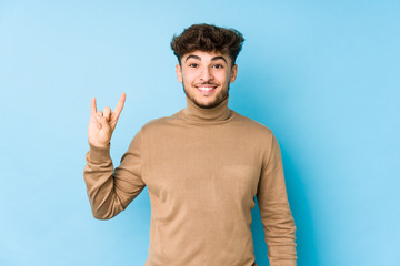 Young arabian man isolated showing a horns gesture as a revolution concept.