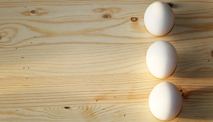 Easter composition on a sunny rustic table. White easter eggs on wooden sunny background. Minimal...