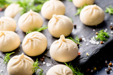 frozen khinkali and dumplings on a dark background with ingredients and spices. Semi-finished products