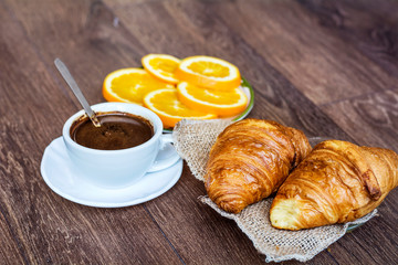 Cup of Coffee and Fresh Baked Croissants for Breakfast on a Wooden Background 