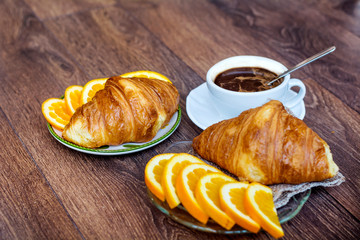 Cup of Coffee and Fresh Baked Croissants for Breakfast on a Wooden Background 